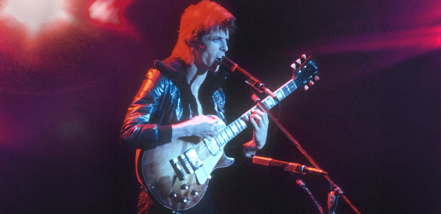 Musician playing electric guitar on stage with colorful lighting.