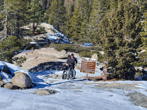 Man bikepacking with loaded down bike at at the bottom of a granite slab with steep slope