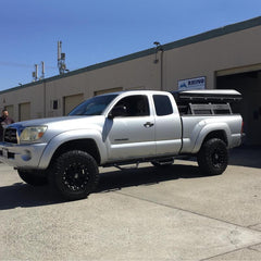 silver 2nd gen Toyota Tacoma with iKamper Roof Top Tent installed on custom rack system in front of Rhino Adventure Gear in California