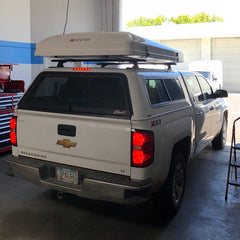 white chevy silverado with white ikamper roof top tent installed on cab