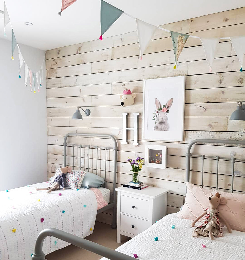 Child's bedroom with twin beds and wood plank walls, picture of a rabbit on the wall