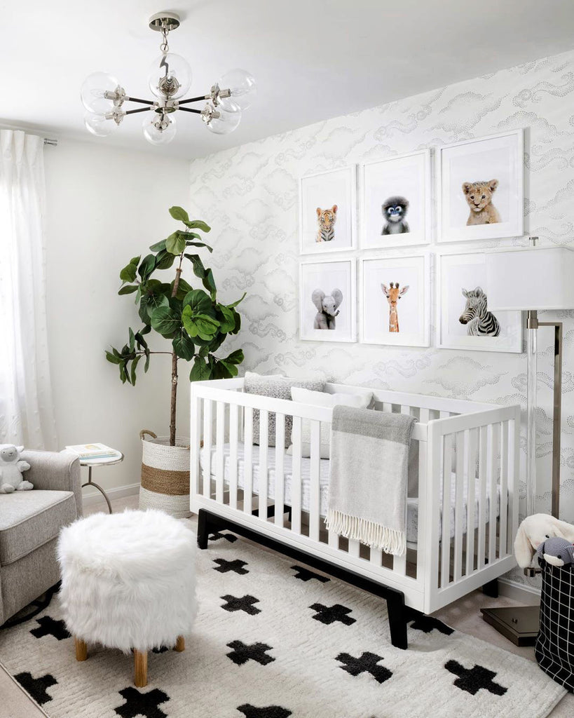 A neutral nursery room with a bold carpet, white crib, and six baby animal prints on the wall