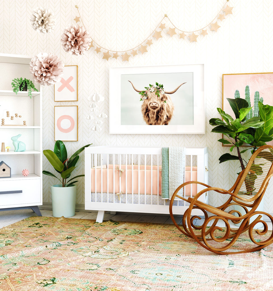 Nursery room with a framed print of a highland cow above the crib, antique rocking chair, subdued pink and blue colors