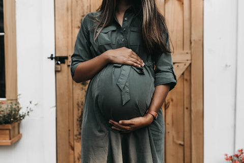 pregnant woman in green dress holding her stomach