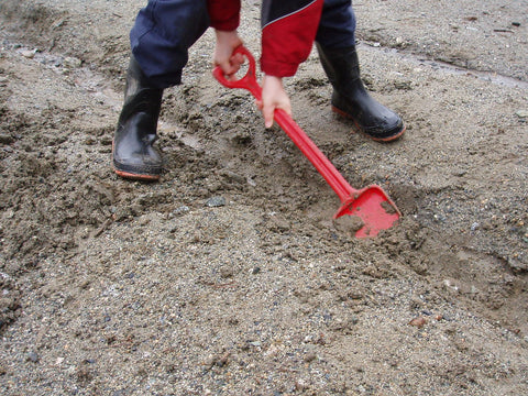 A child digging up dirt with a spade