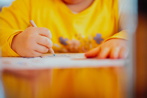 A child drawing with a pencil at a desk