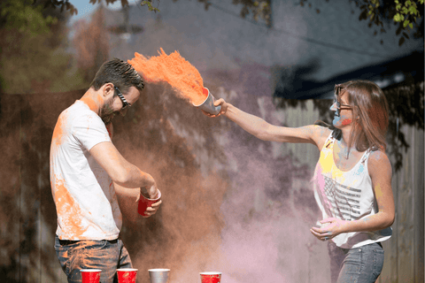 A woman throwing orange colour powder over a male.