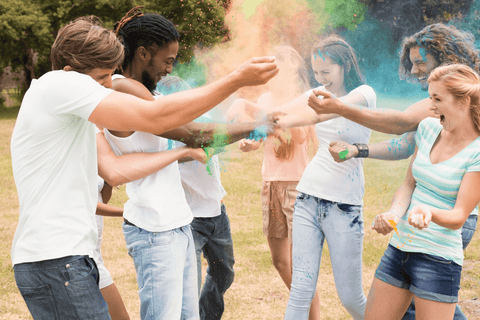 Group of people throwing colour powder in the air.