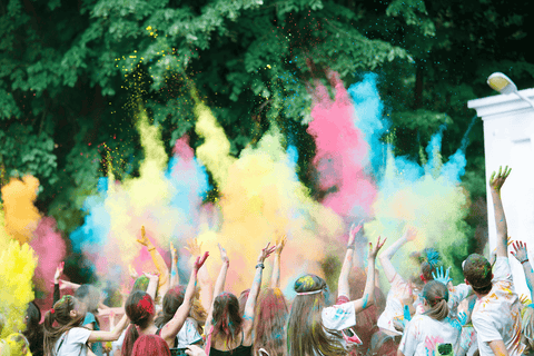 A large crowd of people throwing colour powder outside