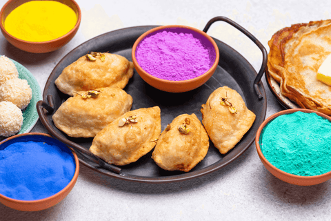 Traditional Indian snack gujiya surrounded by colour powder