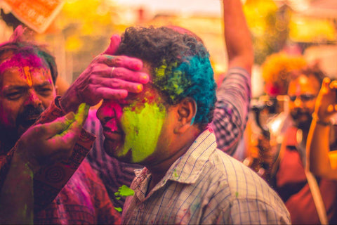 A man having colour powder applied to his face at Holi festival