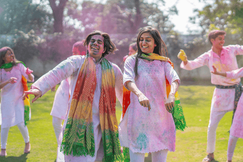 A group of people in traditional Indian clothing throwing colour powder at each other