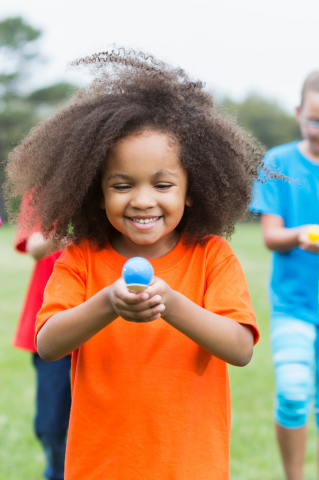 Child holding colourful egg on spoon