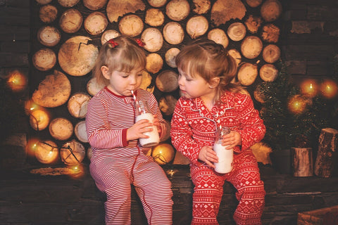 Two girls in Christmas pyjamas drinking milk