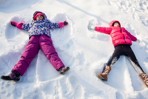 Two girls making snow angels in the snow