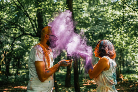 A man and a woman throwing colour powder each other outside