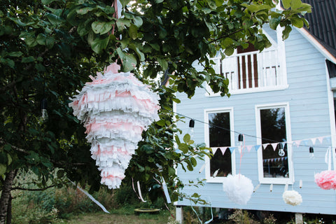 Pink and blue pinata hung up in a garden