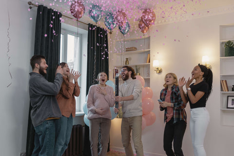 People celebrating a gender reveal with a pink confetti canon