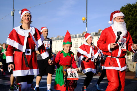 A crowd of people dressed as Santa and elves walking down a street