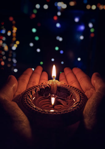 Hands holding a Diya lamp