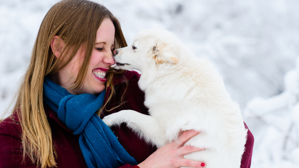 A woman getting a kiss from her white dog that she just got