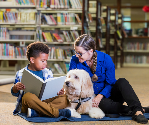 Therapy dog with its owner and a child at a library