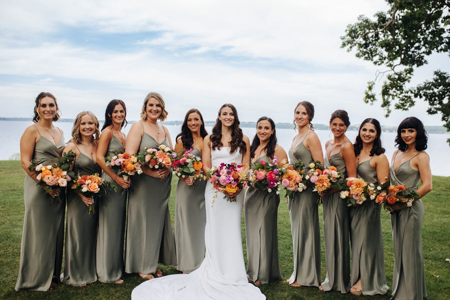 Bridal party in green, bride in white, all holding very colorful bouquets!