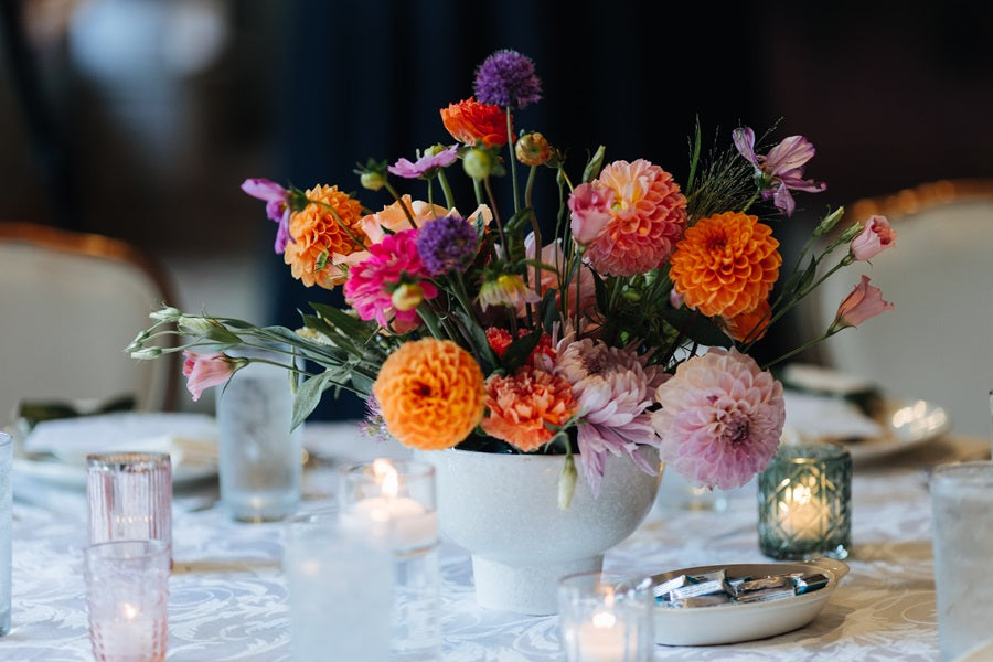 Close up of a bright and colorful floral centerpiece w/ a focus on dahlias and other accent florals.