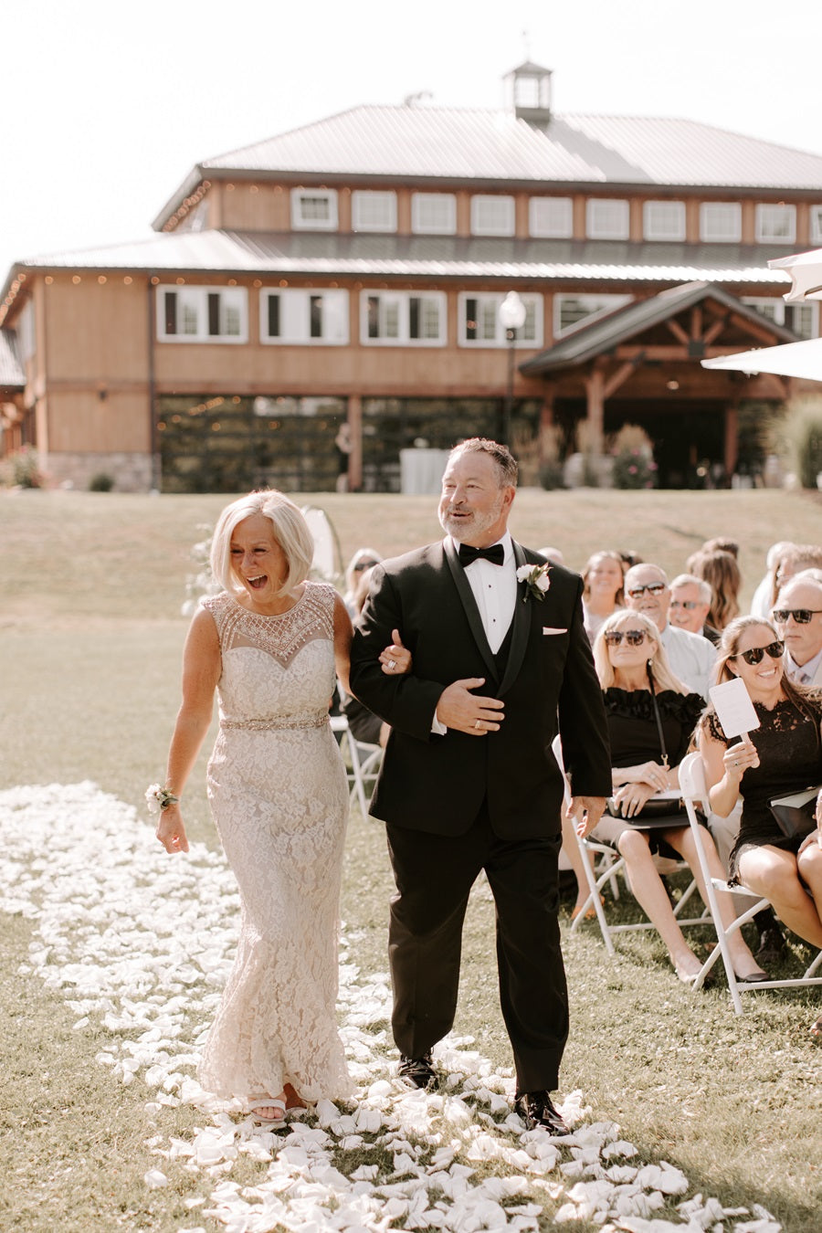 Mother and father (?) walking down the aisle arm in arm on a carpet of flower petals.