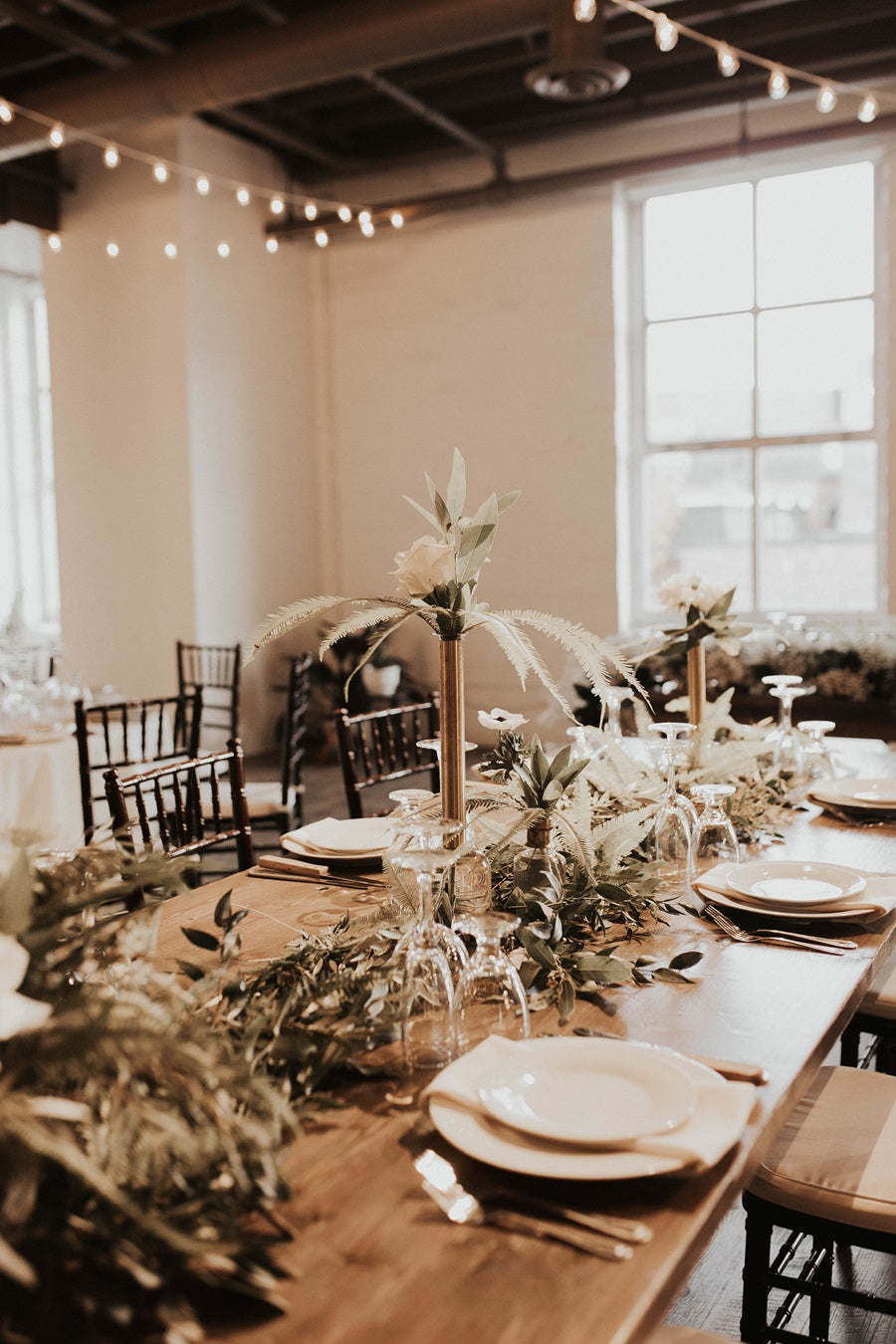 Table with loose greenery, centerpieces, and bud vases. The style is natural and neutral.