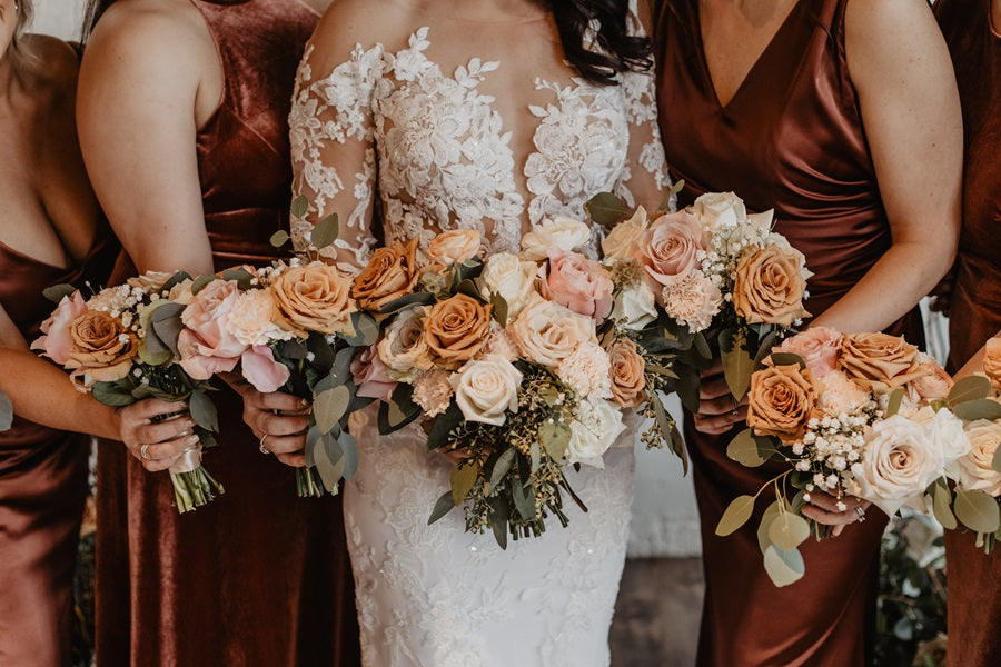 Close up of the bride and bridal party's bouquets. The florals are toffee, cream, light pink, and white, with accent greenery.