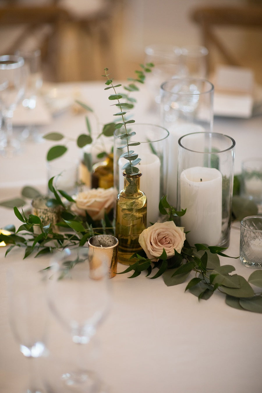 Close up on the loose greenery and floral centerpiece. Accented with neutral candles and votives.