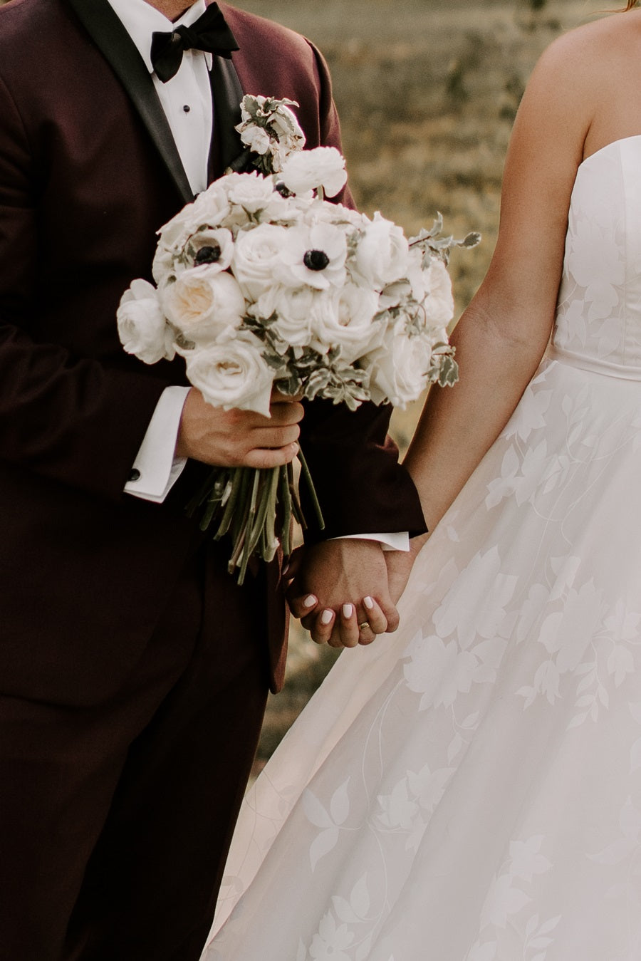 Bride and groom holding hands, groom holds the bridal bouquet this time.