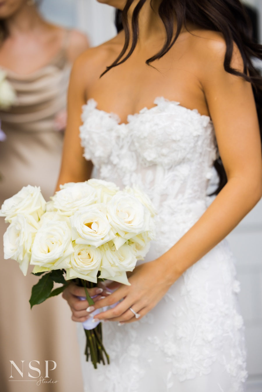 Bride holding bouquet of white roses.