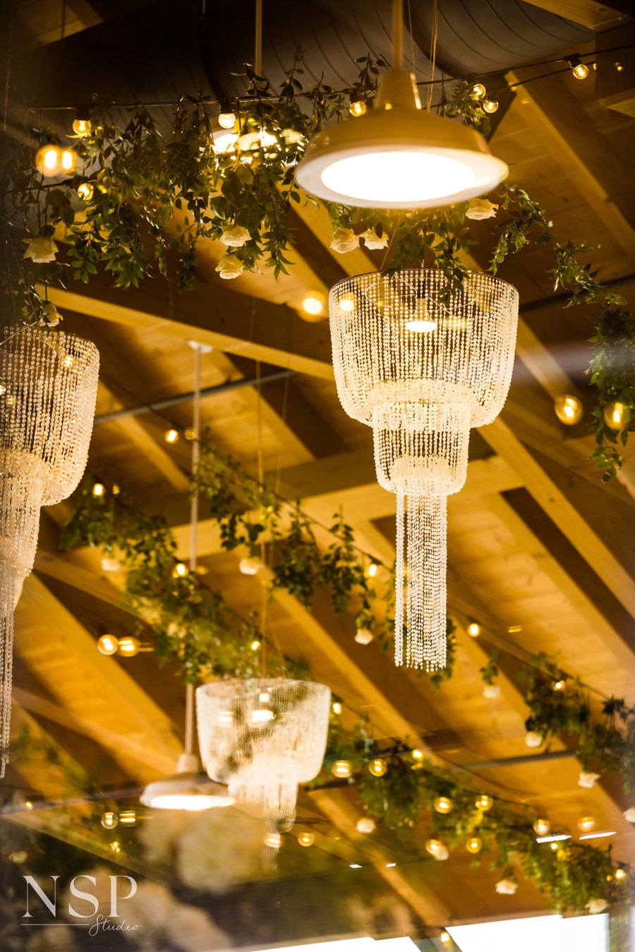 Close up shot of the ceiling, highlighting the chandeliers, string lights, and hanging greenery.