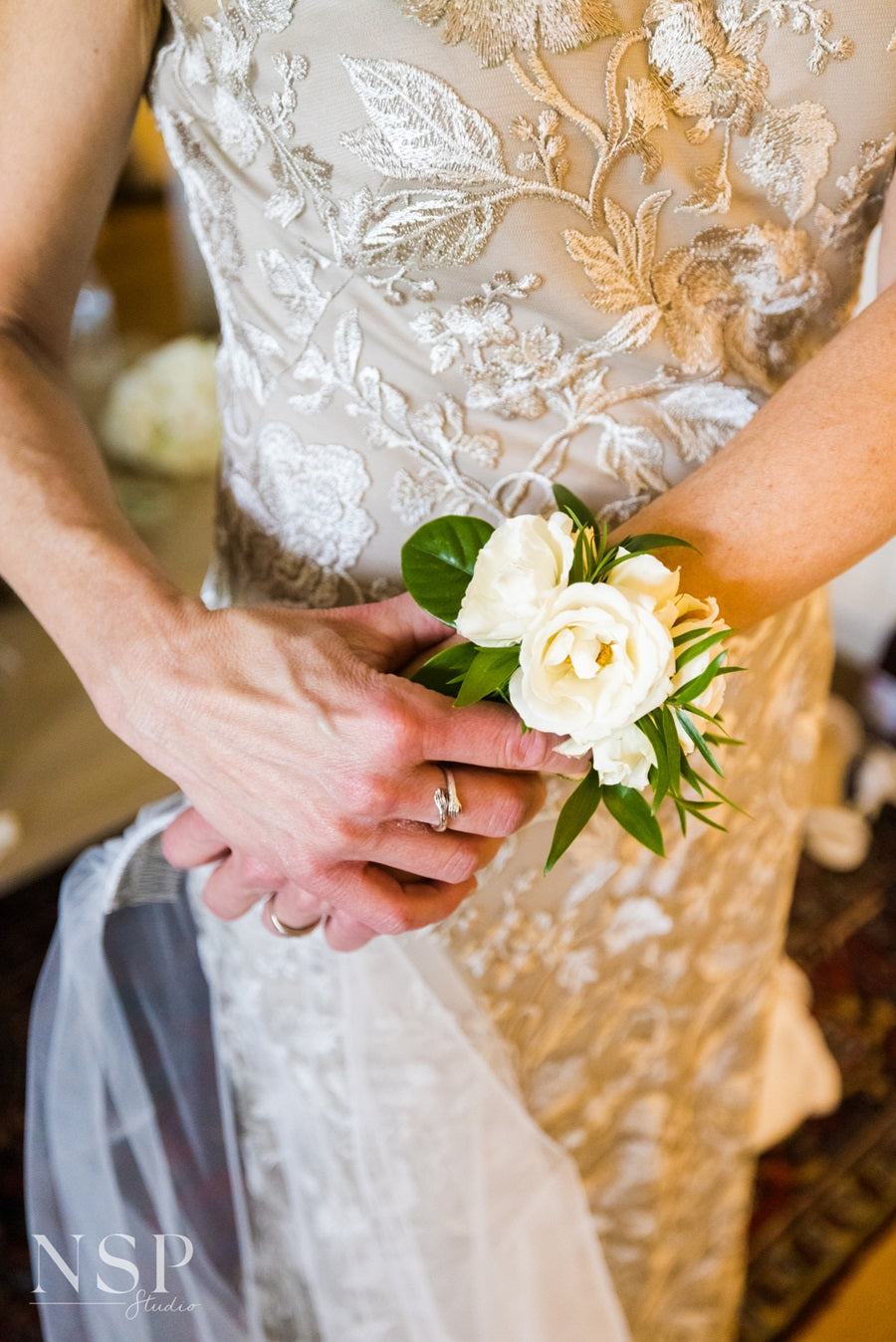 Mother with her white and green floral corsage, holding the bride's vail in her hand.