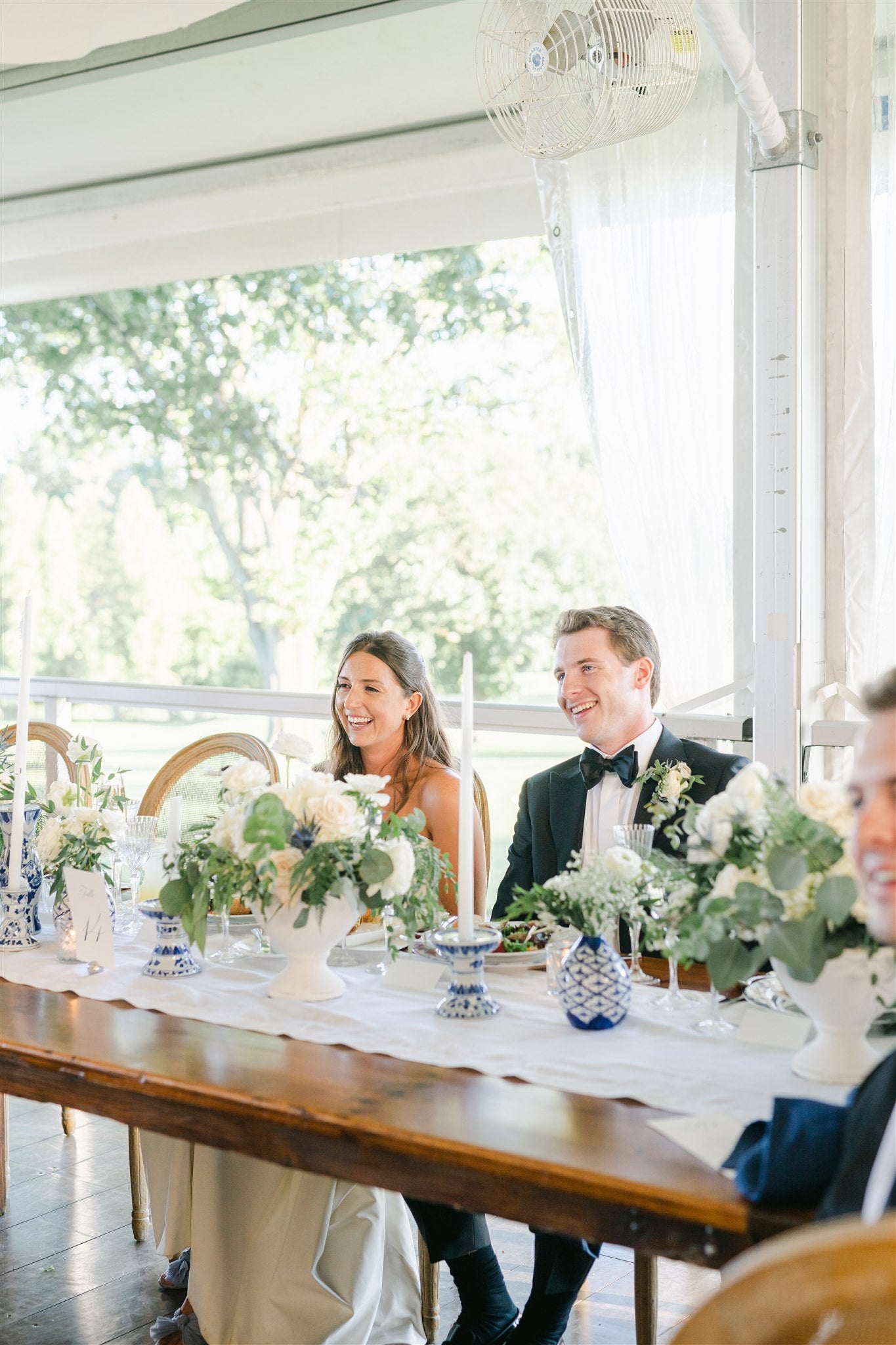 bride and groom sitting at head table 
