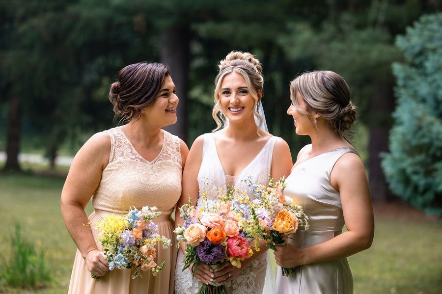 Bride in the middle with bridesmaids on her right and left. holding matching bouquets.