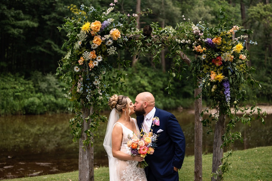 Bride and groom embrace underneath the arch.