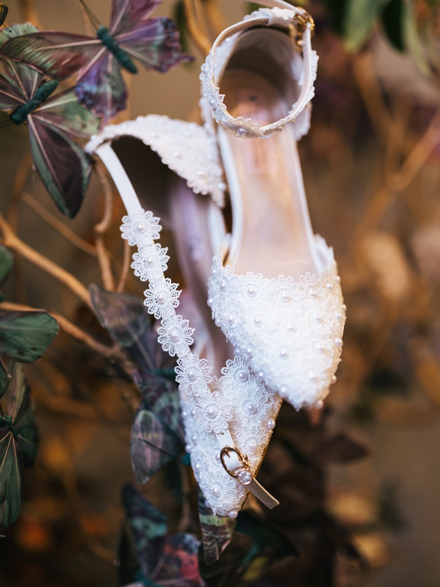 Detail shot of white low heels against a background of butterflies and branching.