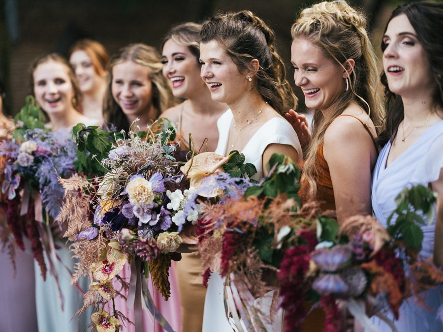 A forced perspective shot of the bridesmaids. Showcases their cascading bouquets with purple, red, green, and yellow. Bride is in the center.