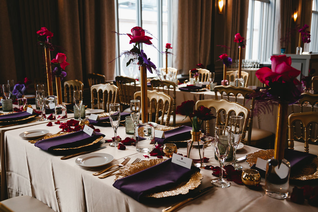 side view of long guest table with red and purple bus vases
