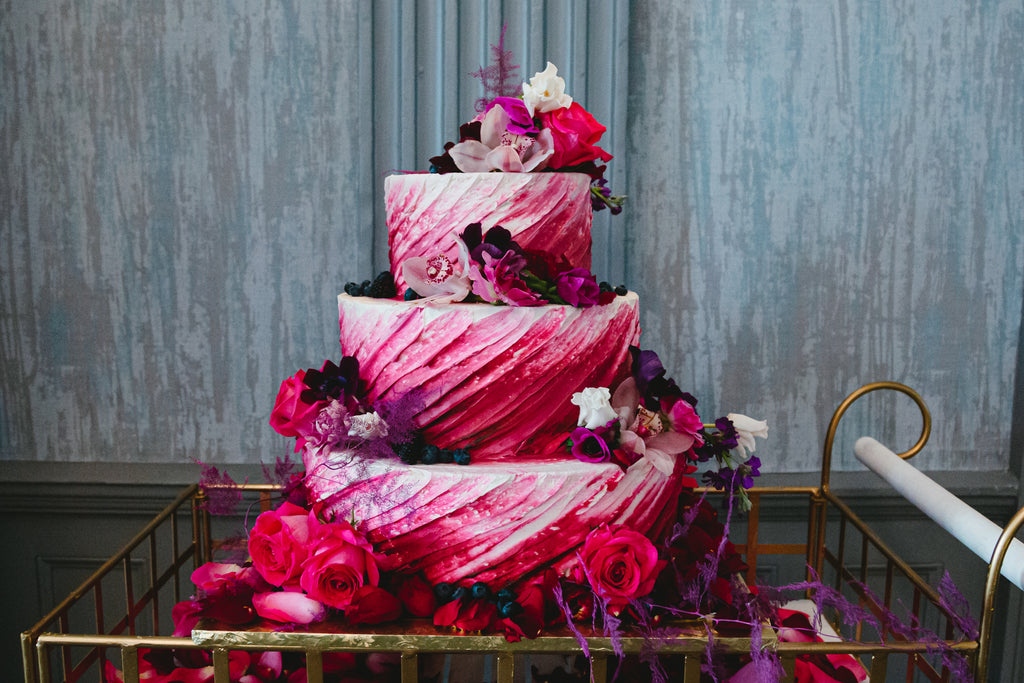 3 tier wedding cake with red and purple flowers 