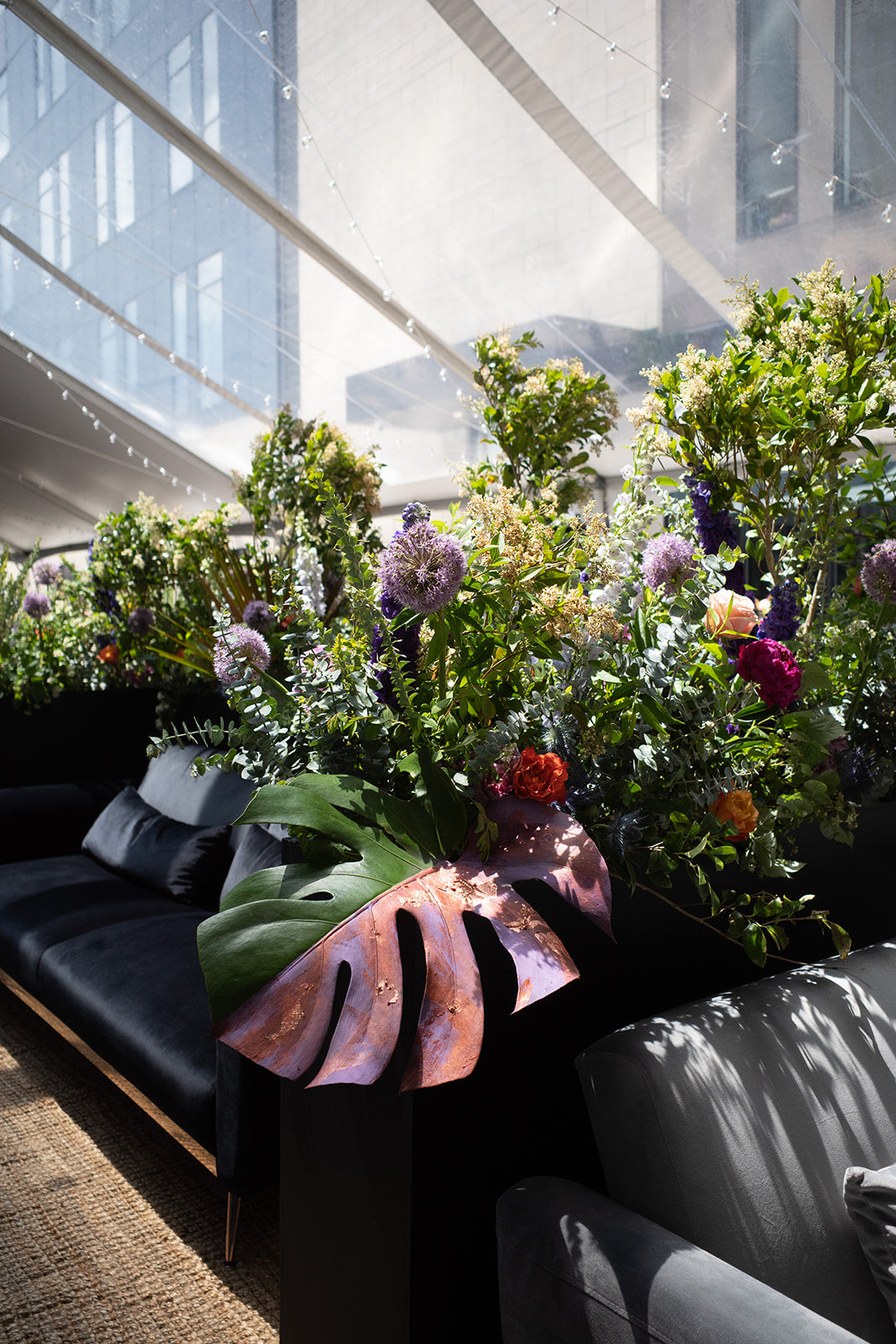 large planters filled with flowers and painted monstera leaves