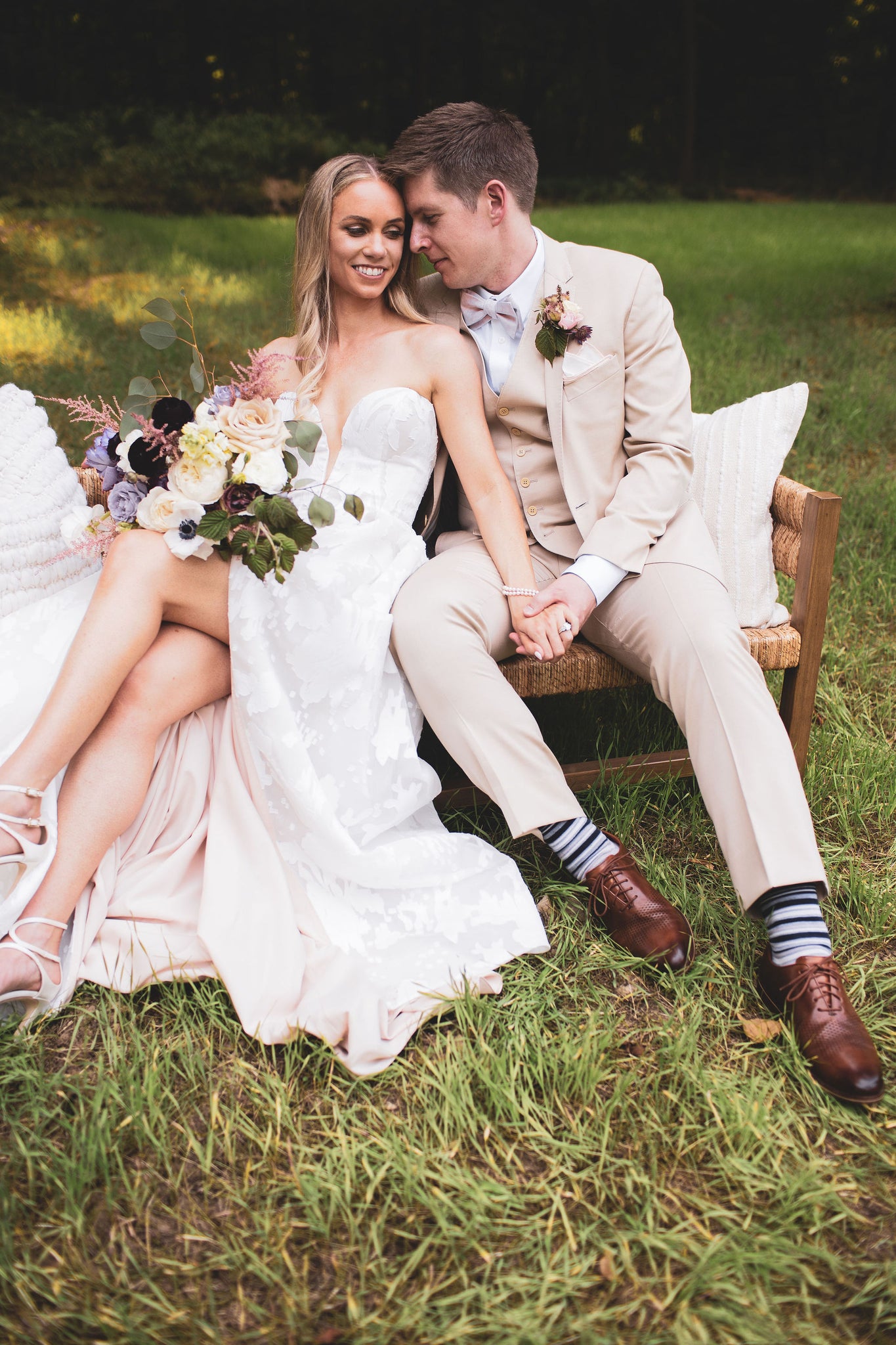 Bride and groom sitting in grass holding hands