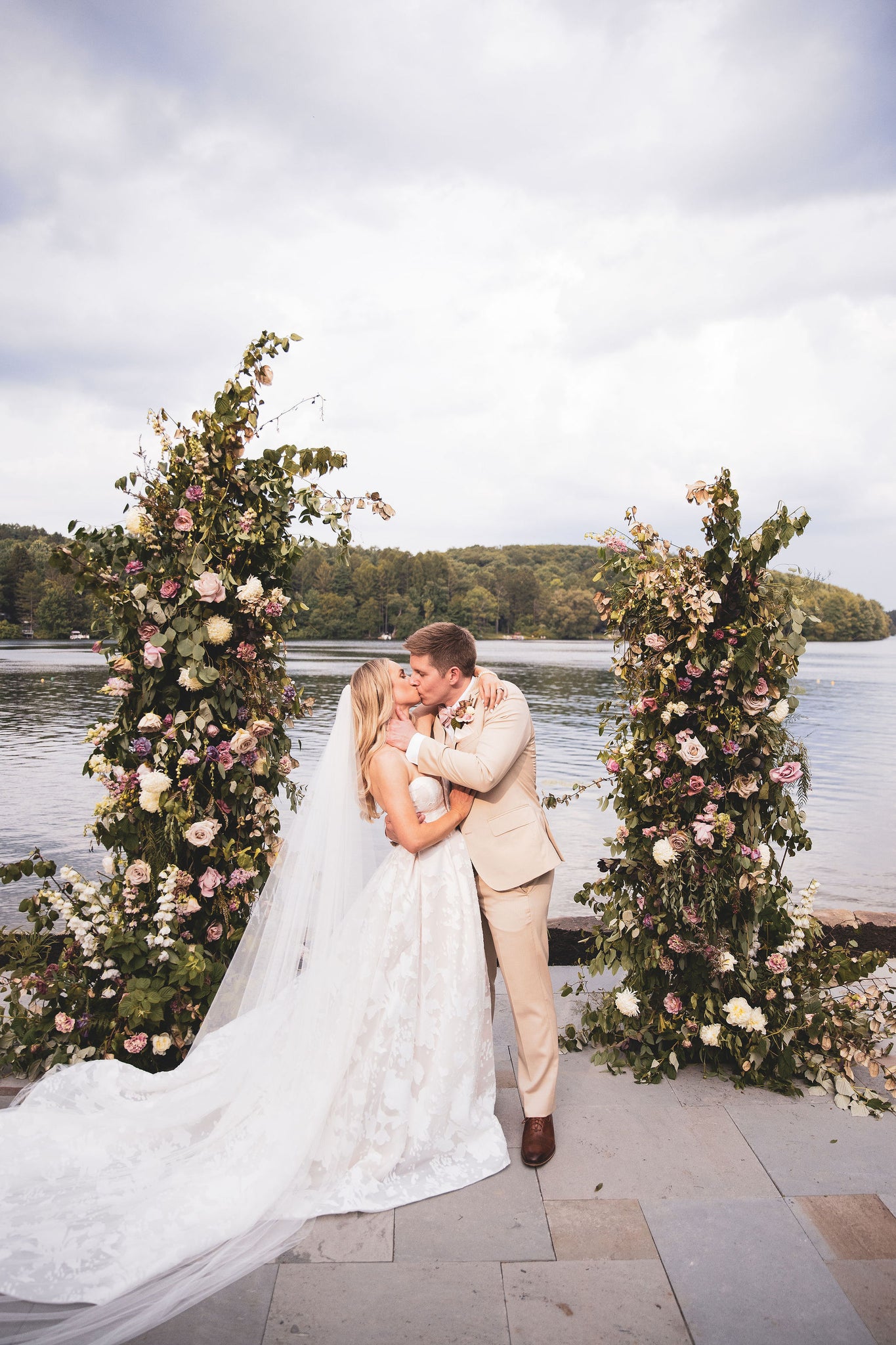 bride and groom kissing under floral arch 