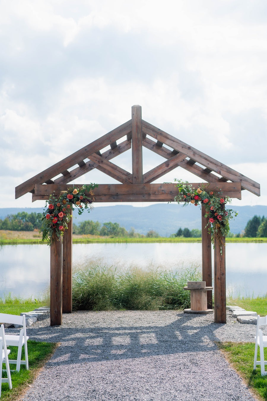 Arbor over a stone walkway at Wrens Roost Barn, over looking a small lake. Decorated with floral arch pieces on the left and right sides.