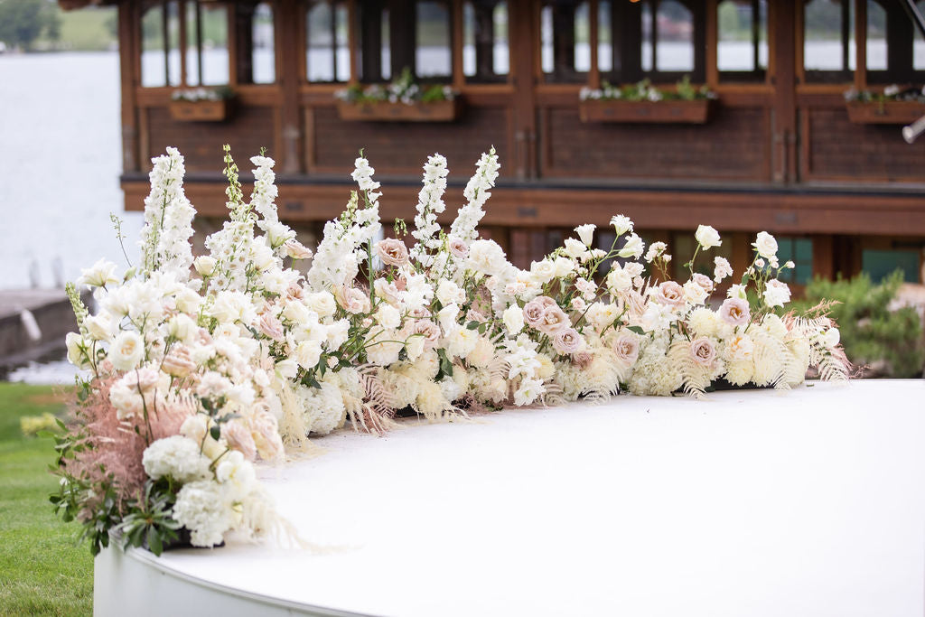 Tall white and peach flowers lining stage