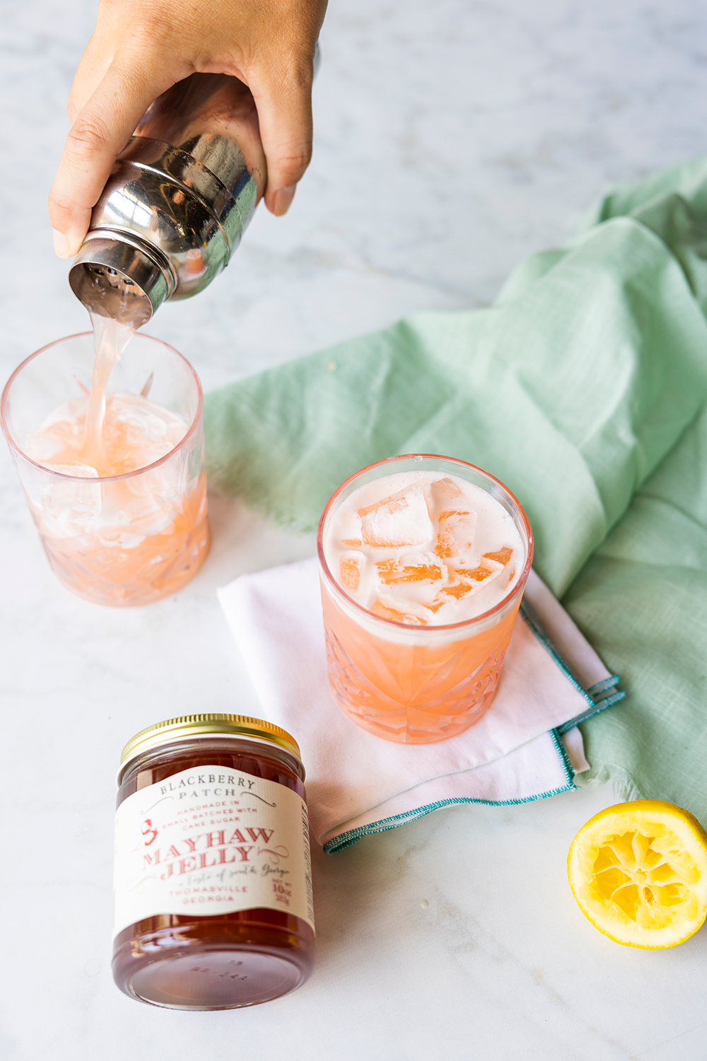 Photo of pouring the Mayhaw Jelly Gin Cocktail into an ice filled glass. 