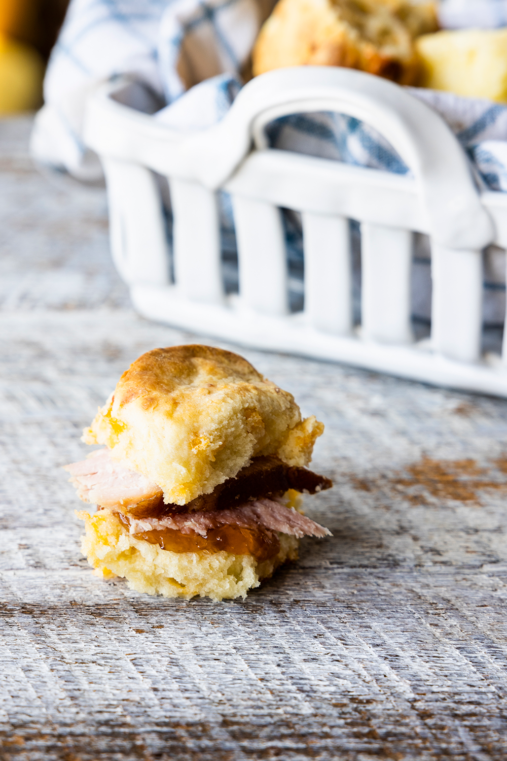 Photo of Mayhaw Jelly Ham Biscuit with basket of biscuits in the background. 